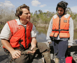 A U.S. Fish and Wildlife Service employee discusses alligators with an intern on a boat