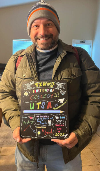 Tino Vanegas smiles while holding a chalkboard that reads "Tino's First Day of College"