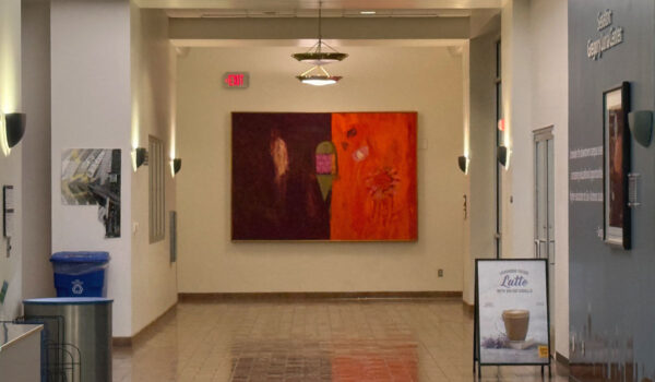 A colorful painting hangs at the end of a hallway