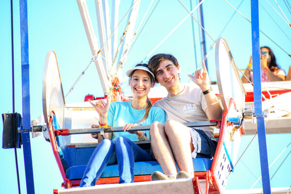 A woman and man sit together in a ferris wheel seat in the sky.