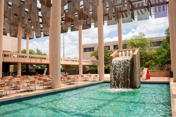A pool of water with a fountain in the middle of a courtyard.