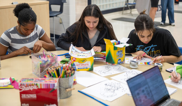 Three individuals sit at a table as they color.