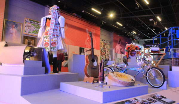 A museum exhibit with a bicycle, a director's chair, a guitar and several other items