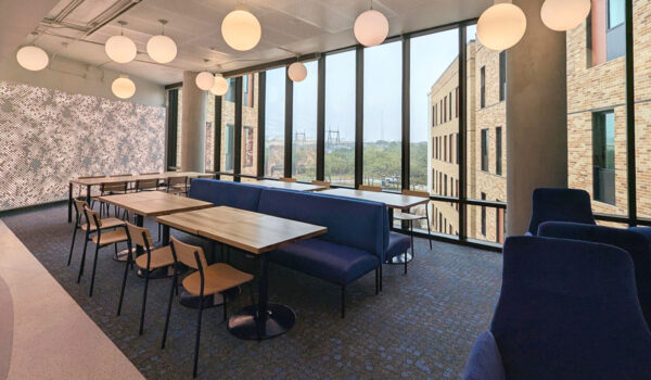 A common area with seats and tables with large windows overlooking the Main Campus