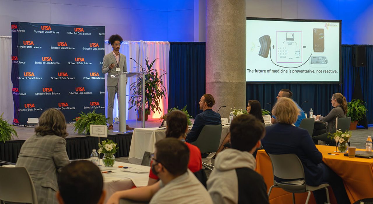 A young male speaker makes his presentation in front of the Draper competition audience