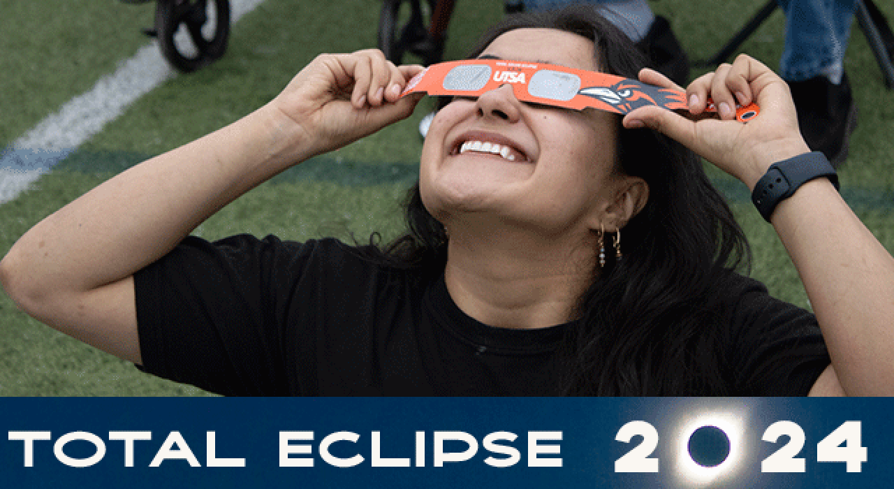 A student showcases his UTSA-branded total solar eclipse shirt and a model of an eclipse. The disco ball is one way to safely view the eclipse