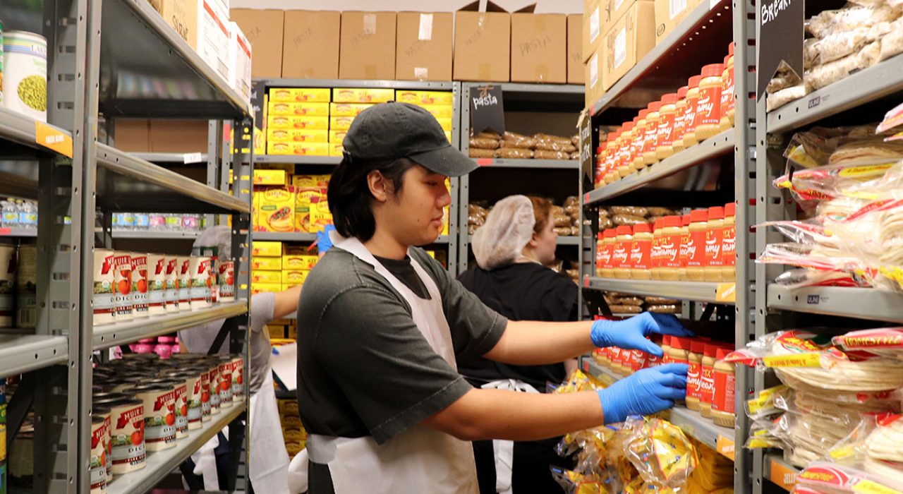 student stocking food pantry shelves