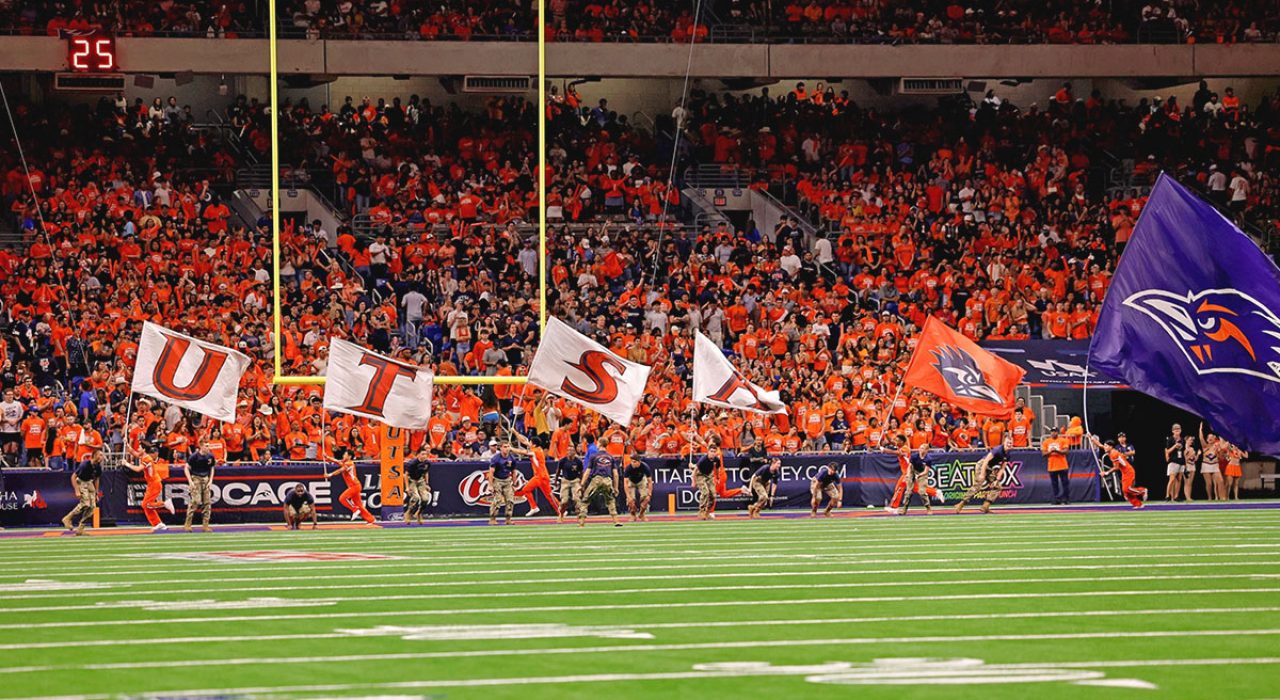 football-alamodome-flags Members of UTSA Cheer carry UTSA flags across the endzone