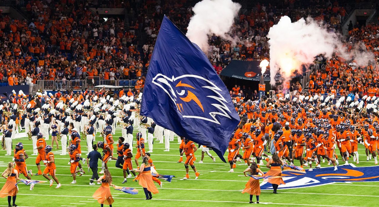 UTSA football team runs on to the field while cheerleaders and the marching band perform