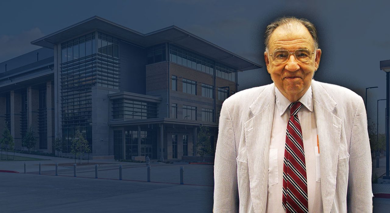 A man in a grey suit with a red striped tie.
