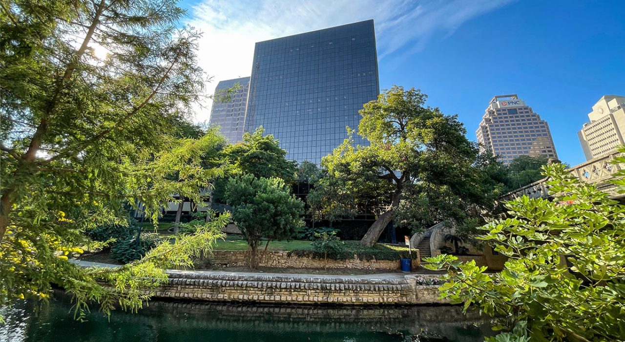 The One Riverwalk Place building towering over the San Antonio Riverwalk below