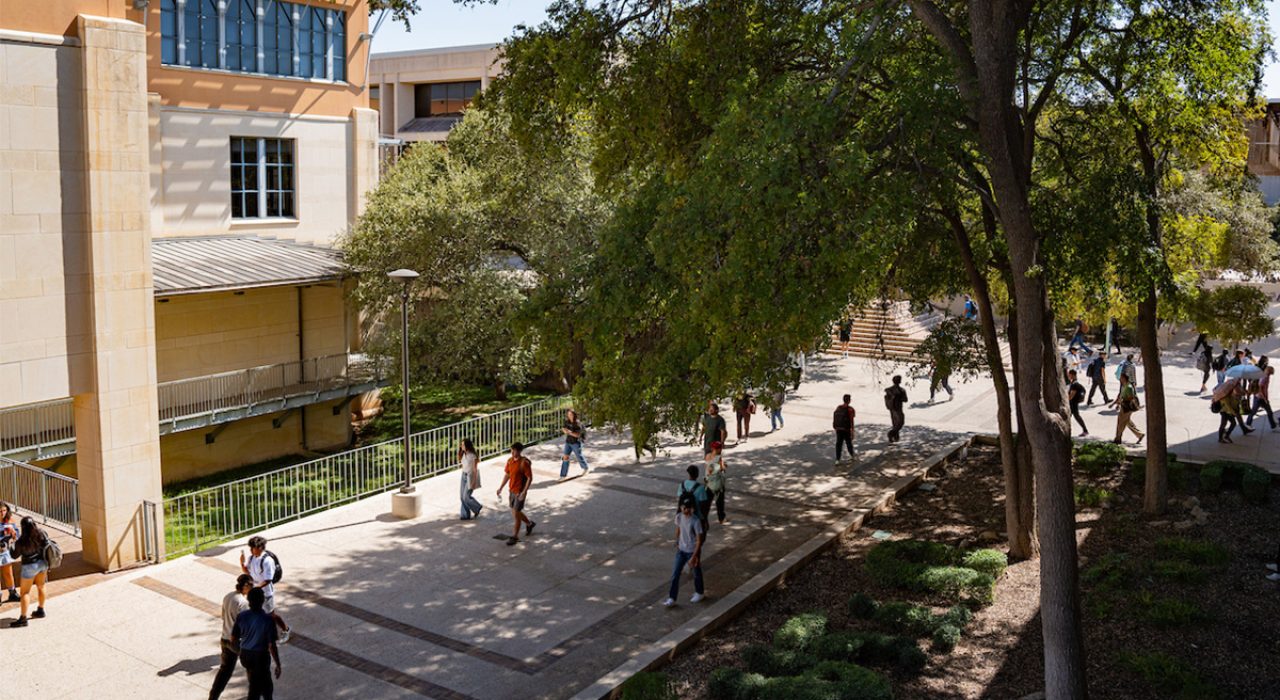 students walking across UT San Antonio campus next to business building