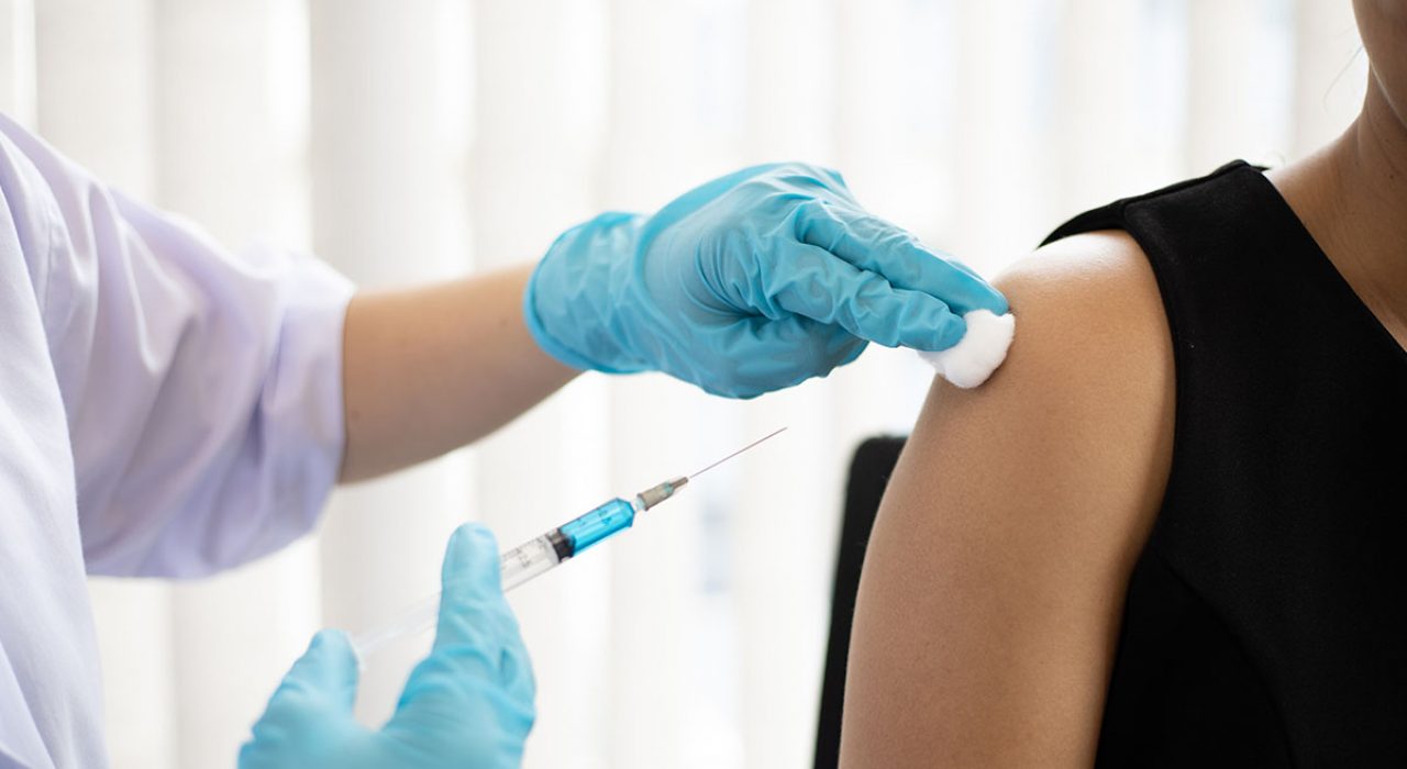 A health professional prepares to put a vaccine needle in a woman's arm