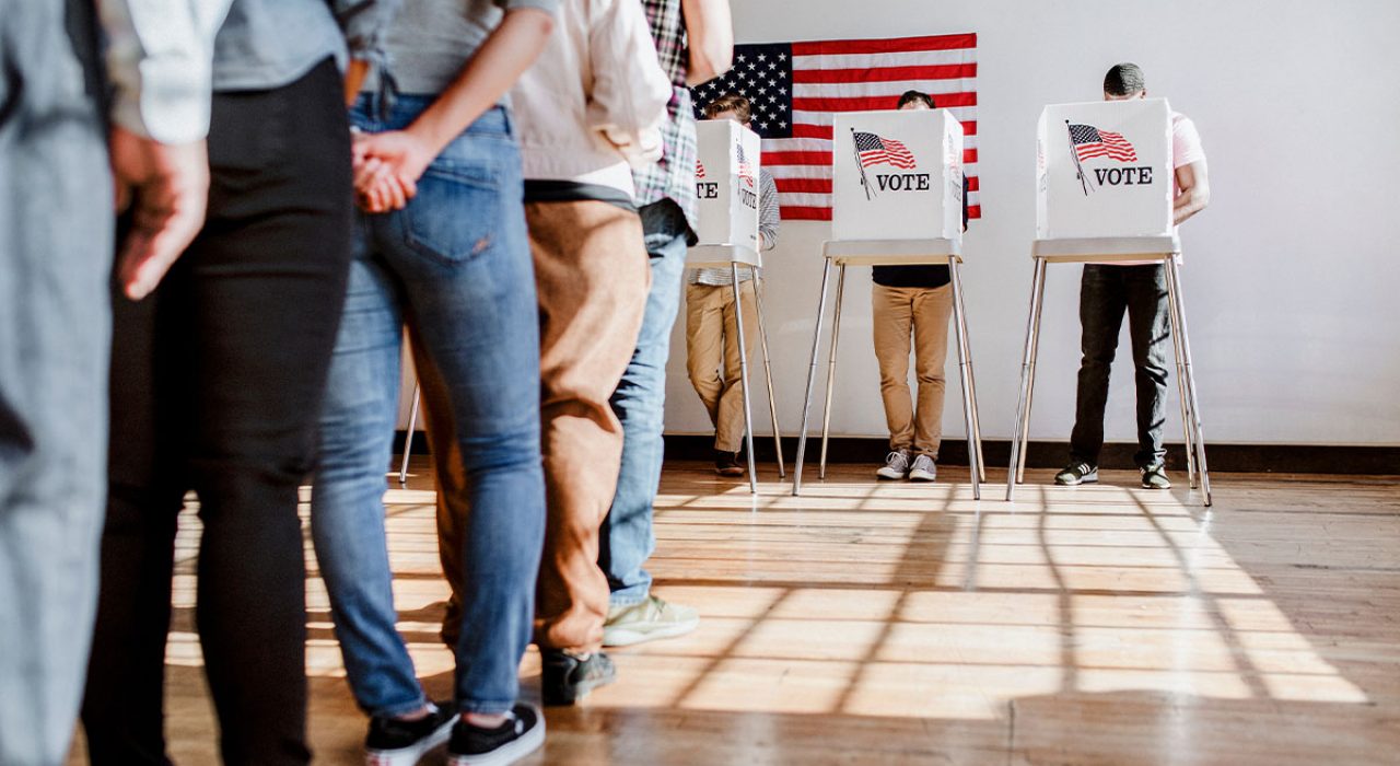 people in line to vote and a flag on the wall